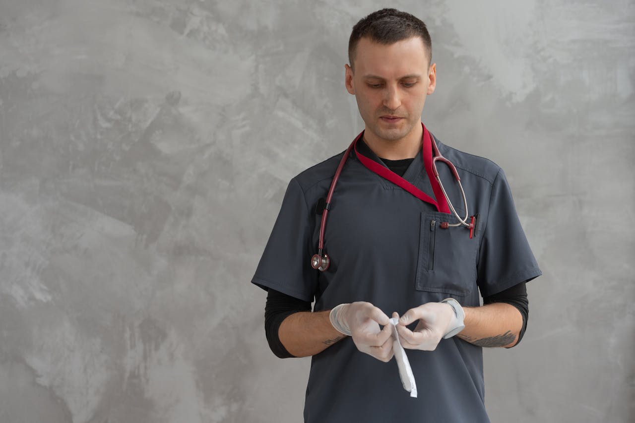 A medical professional with stethoscope and gloves examines equipment indoors.